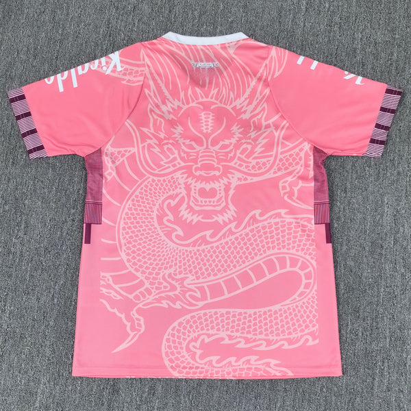 Back view of a bright pink athletic shirt featuring a large white dragon graphic across the back, white collar, and purple plaid sleeve bands.