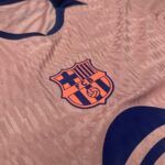 Close-up of pink fabric with an FC Barcelona crest sticker and blue trim nearby.