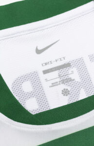 Close-up of white Nike athletic fabric with green trim, showing the gray swoosh and DRI-FIT / SLIM FIT text.