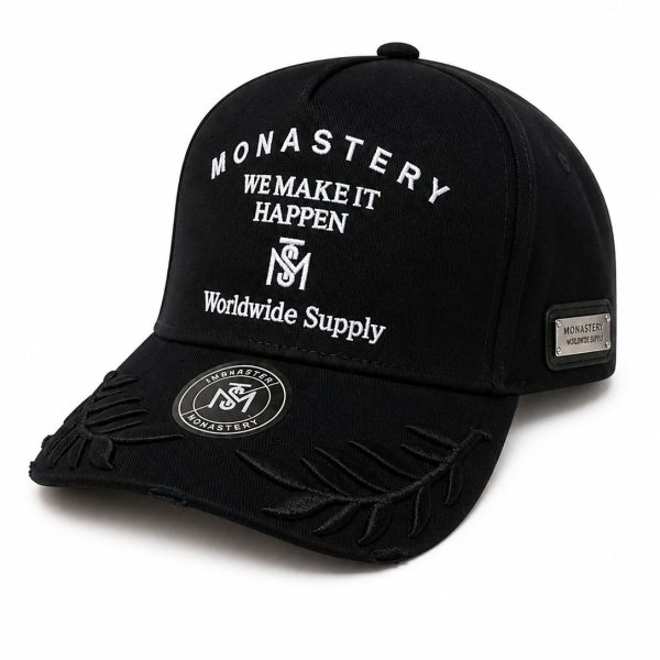 Black baseball cap with white embroidered text: 'MONASTERY WE MAKE IT HAPPEN Worldwide Supply' and decorative stitched brim detail