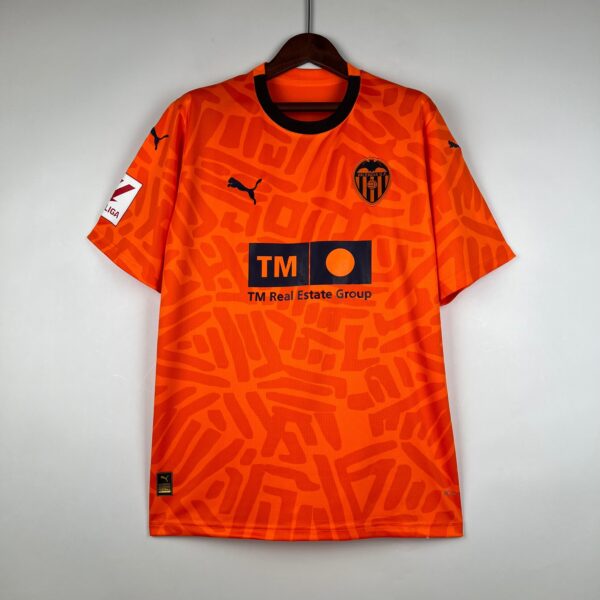 Orange Valencia CF football jersey on a hanger, featuring a black collar and a team crest on the chest left side.