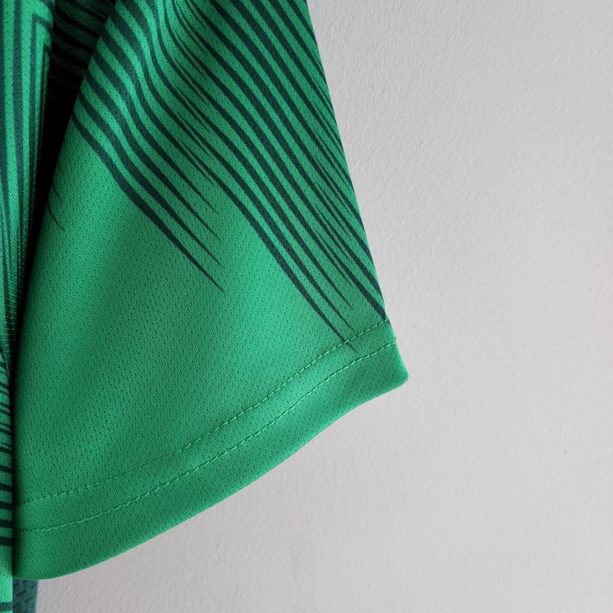 Close-up of a green fabric with dark diagonal stripes, likely a garment sleeve edge.