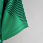 Close-up of a green fabric with dark diagonal stripes, likely a garment sleeve edge.
