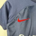 Close-up of dark blue denim fabric with a partial orange Nike swoosh logo visible at the bottom right.