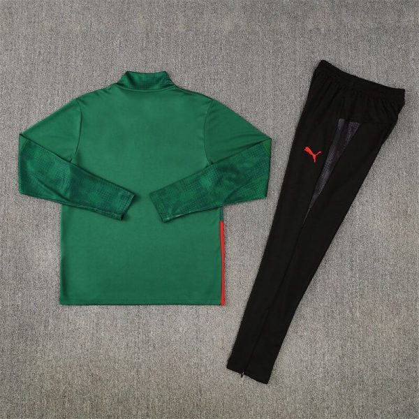 Green long-sleeve athletic shirt with textured sleeves and a red side stripe, paired with black jogger pants featuring a red Puma logo, laid flat on a gray surface.