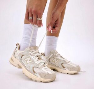 00f7f32a-b6e9-4a54-b1f2-d6ea58ae1a6c | UAE SPORT STORE Person tying the laces of chunky beige sneakers with white socks visible above the shoes
