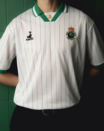 01-2web_400x_a9d387f9-d9ab-49cf-933f-0b0c6b1d60b1 | UAE SPORT STORE Person wearing a white polo shirt with green collar and cuffs, featuring a crest badge on the left chest.