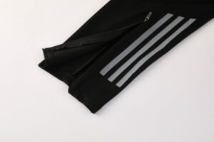 Black athletic pants with three reflective grey stripes along the leg and an ankle zipper detail.