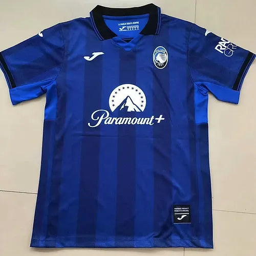Front view of a blue striped soccer jersey with Paramount+ sponsor across the chest, team crest on the left chest, and Joma logo on the right.