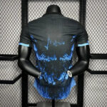 Back view of a black athletic t-shirt with a blue flame-like splash design on a mannequin torso, on a gym display rack.