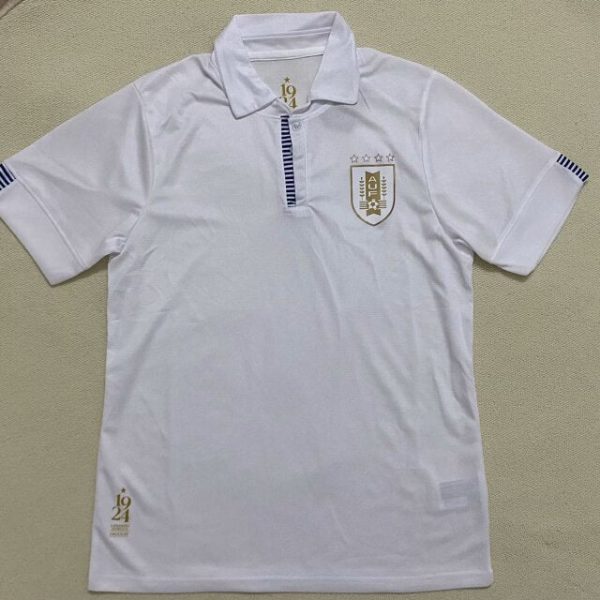 White polo shirt with a blue striped placket, left chest crest with five stars, blue-and-white striped sleeve cuffs, and a small gold '24' graphic at the bottom left hem.