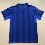 Back view of a blue soccer jersey with dark vertical stripes, short sleeves, on a tiled floor with a black collar.