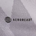Close-up of light gray knitted fabric with a small black globe emblem in the bottom-left corner.