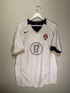 Portugal national team white soccer jersey with gold piping and crest on the left chest, hanging on a hanger.