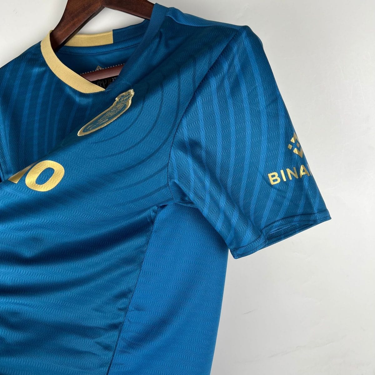 Blue garment on a wooden hanger with gold trim and a metallic emblem visible on the chest area.