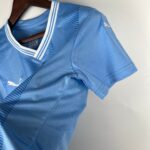 Blue athletic jersey on a hanger, showing a white-striped collar and subtle fabric texture with a small white logo on the sleeve.
