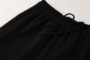 Close-up of black athletic shorts waistband with elastic and drawstring edge.