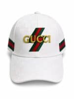 White Gucci baseball cap with embroidered gold logo and green-red-green stripe accents on the front and sides.