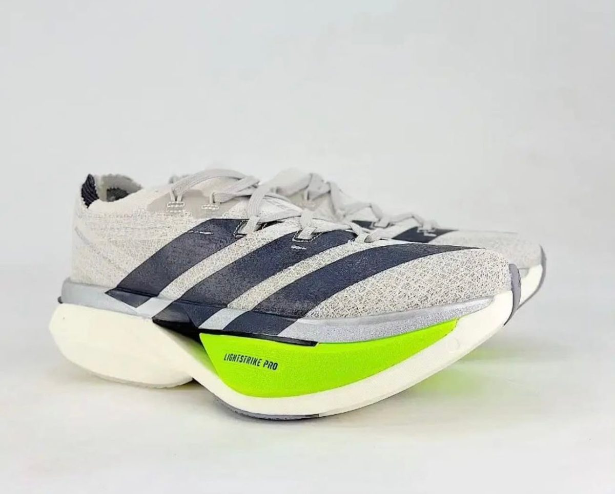 Gray and white athletic running shoe with a bright lime-green midsole and dark stripes along the side (front-right view)