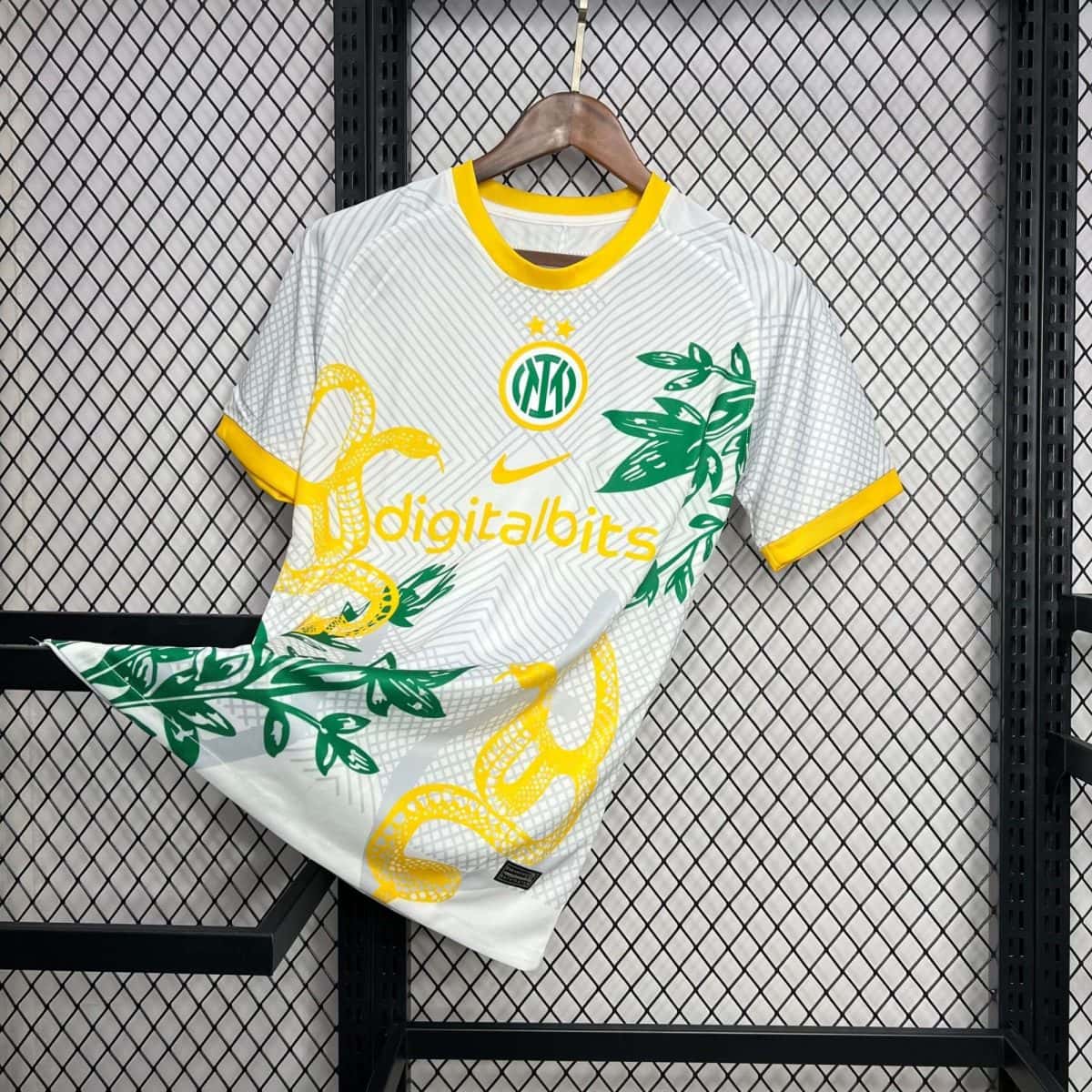 White jersey with yellow trim on a wooden hanger, featuring green leaf graphics against a black metal grid display background.