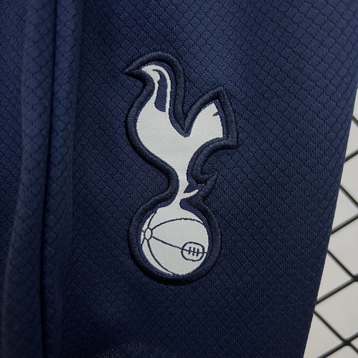 Close-up of dark navy fabric with an embroidered white and light-blue curved emblem patch.