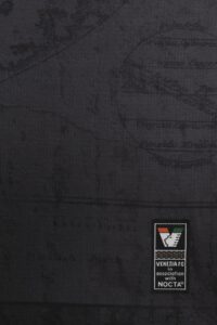 05_Home_Shirt_Cynar_Spritz | UAE SPORT STORE لقطة مقرّبة لقماش داكن مع رقعة مستطيلة صغيرة تُظهر Venezia FC بالتعاون مع علامة NOCTA.