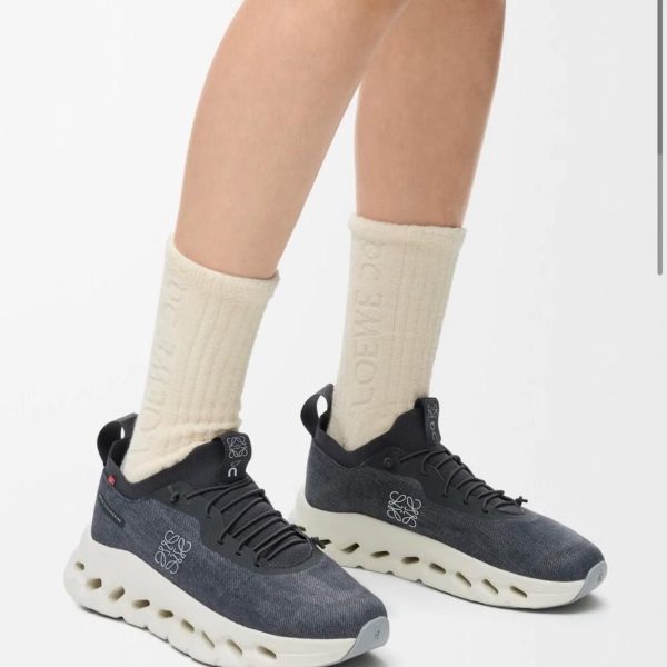 Lower legs wearing dark gray knit sneakers with a chunky white sole and cream crew socks.