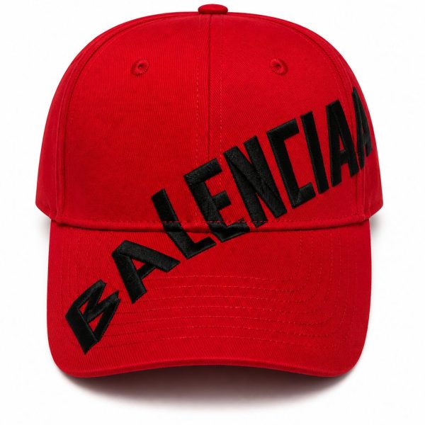 Red baseball cap with bold black 'BALENCIAGA' lettering across the front diagonal path from brim to crown surface.