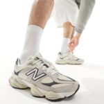 Person wearing white athletic sneakers and tall white socks bends to stretch their ankle behind them in a bright white setting.