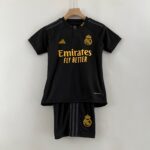 Black Real Madrid football jersey on a wooden hanger with gold crest and sponsor text Emirates Fly Better visible.