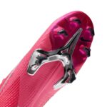 Close-up of a bright pink soccer cleat sole with metal plate and black studs