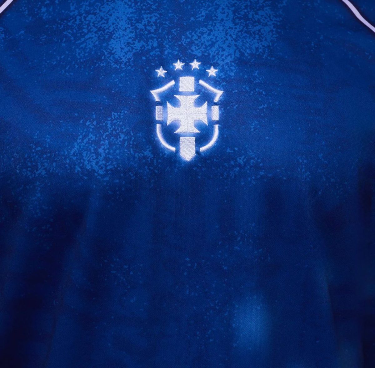 Blue athletic jersey fabric with a white embroidered crest: a shield and cross motif with five stars above.