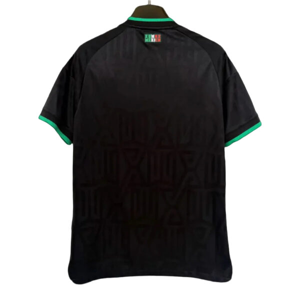 Back view of a black short-sleeve shirt on a hanger, with green trim at the collar and cuffs and a subtle geometric pattern on the fabric.