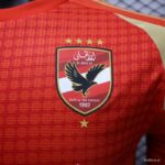 Red Al Ahly FC jersey showing the club crest with a black eagle, four gold stars above and one star below the shield.