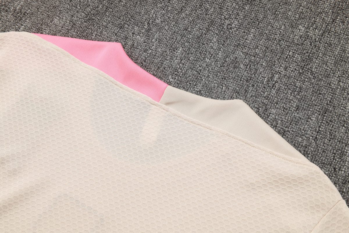 Beige textured fabric with pink trim on a gray carpet background.