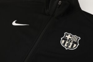 08eec576 | UAE SPORT STORE Close-up of a black jacket showing a white Nike swoosh and an FC Barcelona patch/crest near the zipper area.