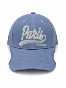 Blue baseball cap with white embroidered 'Paris' script and 'Balenciaga' logo on the front panel; curved brim and structured crown.