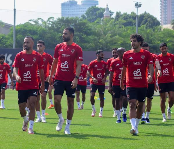 09ae38f2-d19b-477f-8b9b-3f7cf09800c6 | UAE SPORT STORE Soccer players in red jerseys walk on a grassy training field during practice.