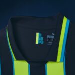 Close-up of a dark jacket with neon yellow and blue reflective stripes and a label reading 30 MAY 1999.
