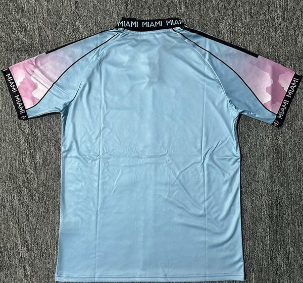 Light blue short-sleeve sports jersey laid flat, back side up, black collar with 'MIAMI' and pink camo panels on the sleeves.