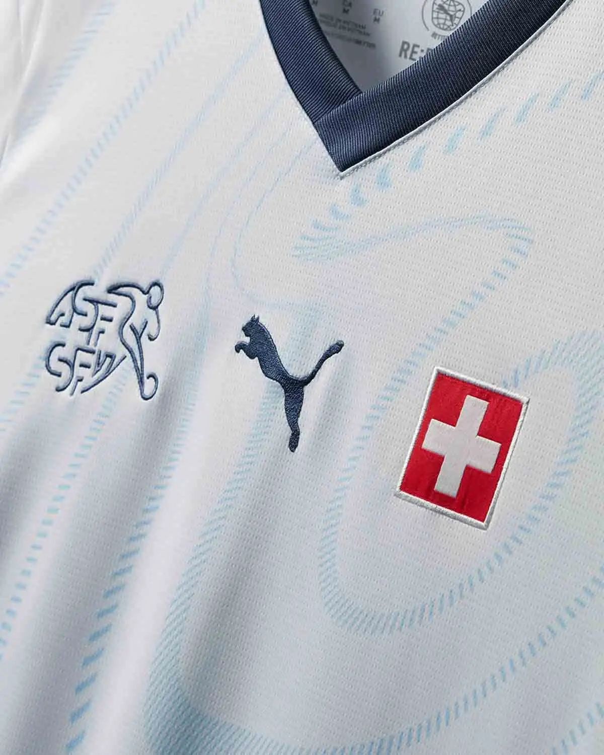0GTXGU92OeJFnO8 | UAE SPORT STORE Close-up of a white Switzerland football jersey showing the Swiss flag badge and sponsor logos (Puma and federation crest).