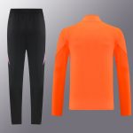 Black athletic pants with pink accents paired with a bright orange long-sleeve top, shown flat as a sportwear set for training.