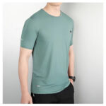 0a78aaab | UAE SPORT STORE Man wearing teal short-sleeve athletic T-shirt with a small chest logo, standing against a light backdrop.