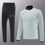 Black Nike joggers with a white swoosh and a light gray quarter-zip training top with a black collar.
