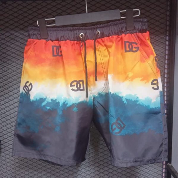 0a8fe0ae-c4e0-4bef-ba44-0cead1a3cf03 | UAE SPORT STORE Colorful men's swim trunks with an orange-to-blue gradient and repeating logos, hanging on a hanger on a display rack.