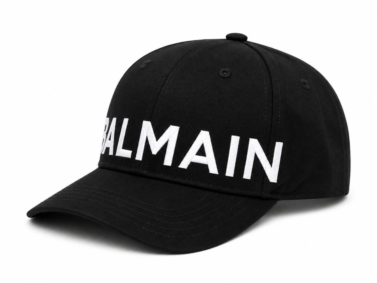 Black baseball cap with a curved brim and a bold white BALMAIN logo across the front.