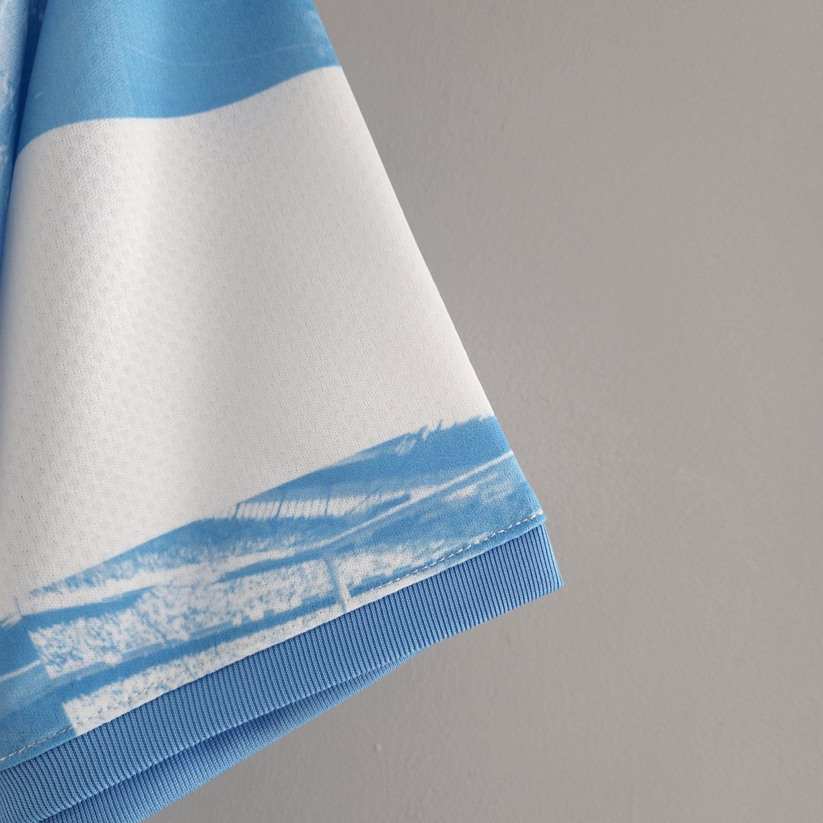 Close-up of a light blue and white striped fabric cuff on blue denim, set against a gray background.