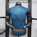 Back view of a blue patterned sports jersey on a mannequin, with orange text near the lower back reading SORGESANA and small orange text SSC NAPOLI at the neck area.