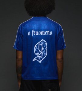 0b22584f-85ee-45fa-8071-1cb8ab4b3a07 | UAE SPORT STORE Back view of a blue sports jersey with white text 'o fenomeno' and a decorative white number nine emblem.