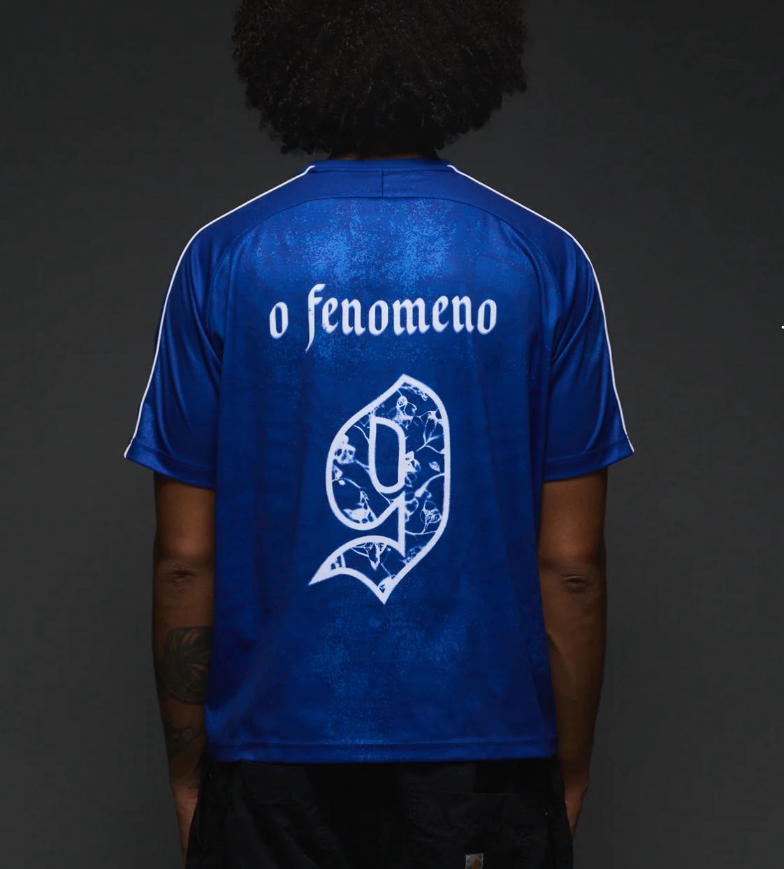 0b22584f-85ee-45fa-8071-1cb8ab4b3a07 | UAE SPORT STORE Back view of a blue sports jersey with white text 'o fenomeno' and a decorative white number nine emblem.